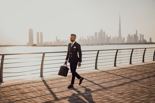 Man wearing a black suit walking by the riverside